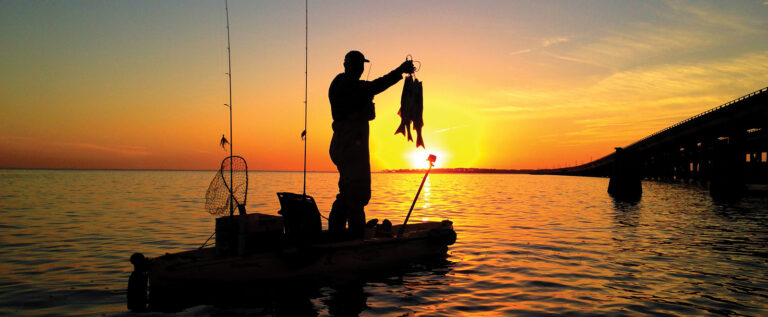 Ryan Rhodes in a Hobie fishing Kayak holding up two catches