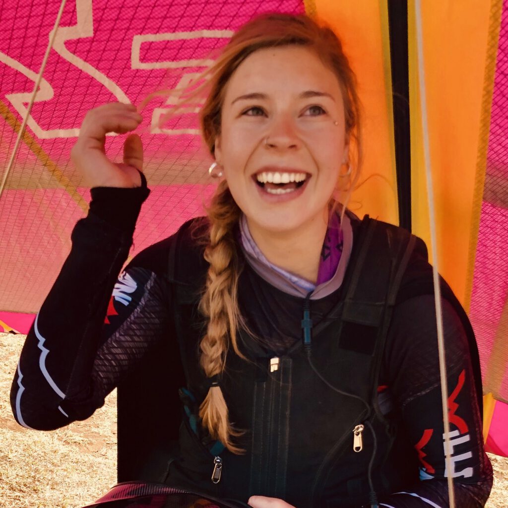Sara smiling with her hang glider at goal on day 4.